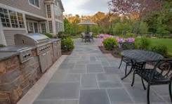 Pattern-cut thermal bluestone tying together an outdoor kitchen and dining terrace.